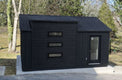 Black shed with a glass door in a garden setting