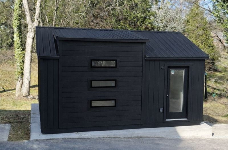 Black shed with a glass door in a garden setting